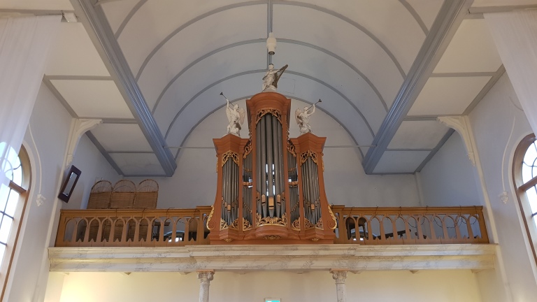 Historisch kerkorgel met beeldhouwwerken van engelen op een galerij in een kerk.