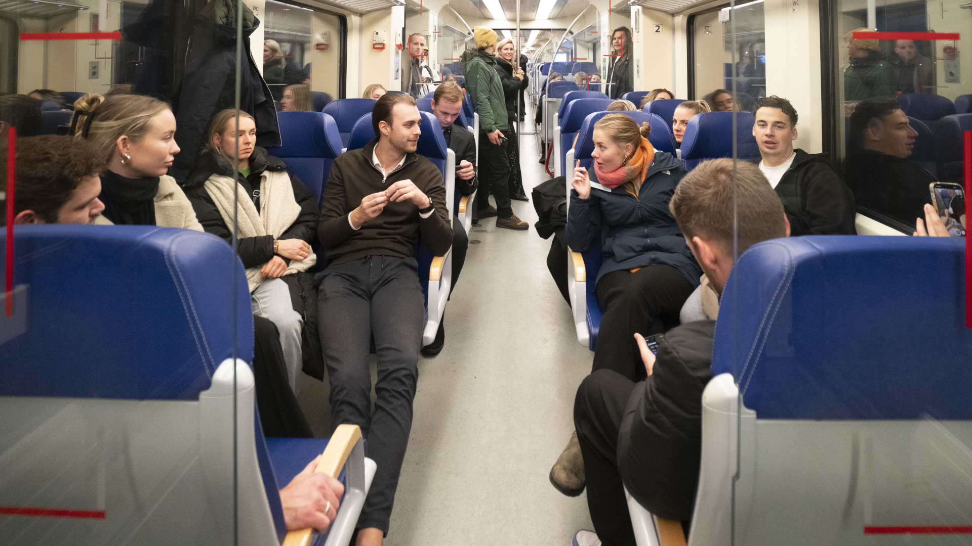 Mensen zitten in een trein en voeren gesprekken.