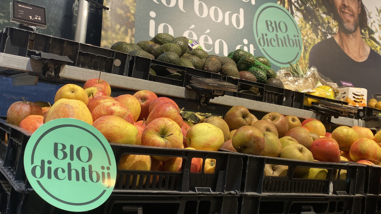 Bak met biologische appels en avocado's in een winkel, met een "BIO dichtbij" bordje.