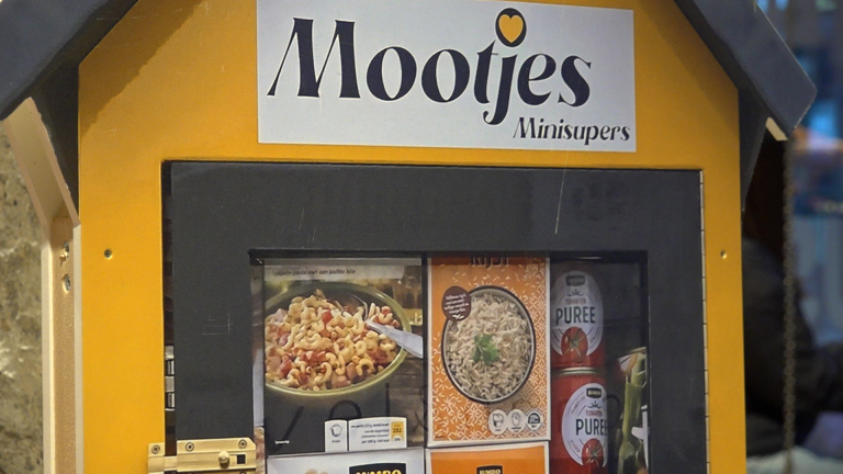 Een mini-supermarkt kastje van "Mootjes Minisupers" gevuld met diverse voedingsmiddelen, waaronder pasta, rijst en tomatenpuree.