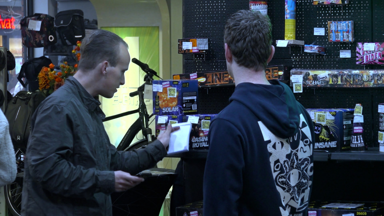 Twee mannen bekijken vuurwerkproducten in een winkel.