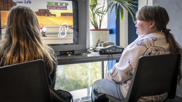 Twee meisjes spelen een videospel op een oude spelcomputer met CRT-televisie.