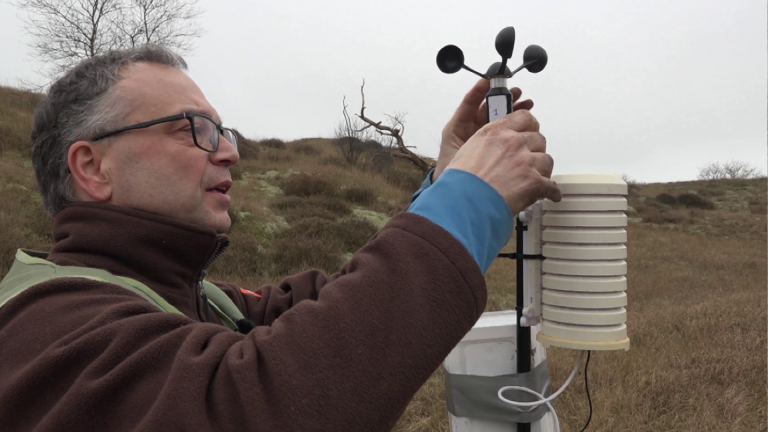 Man installeert een anemometer in een veld.