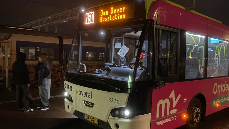 Een bus met lijnnummer N50 naar Den Oever Busstation staat bij een perron met enkele mensen die ernaast staan.