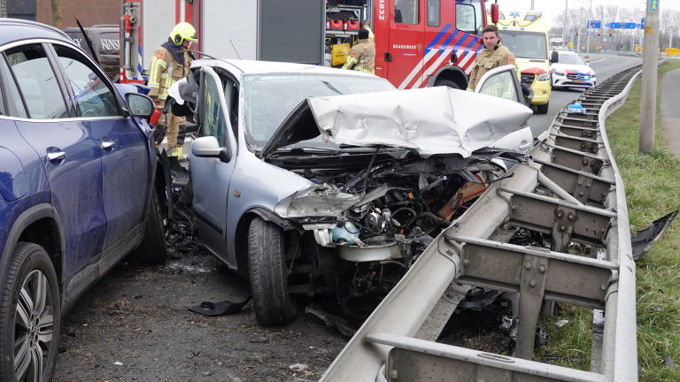 Auto-ongeluk met meerdere voertuigen, beschadigde vangrail en hulpdiensten ter plaatse.