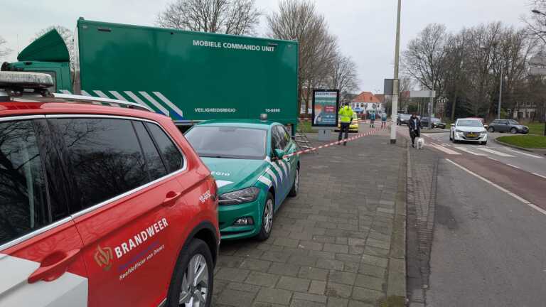 Mobiele commandowagen en voertuigen van de veiligheidsregio en brandweer staan geparkeerd langs een straat met afzetlint.