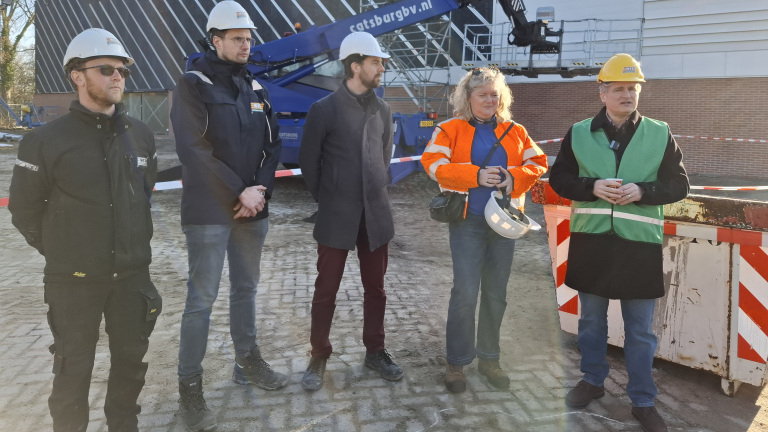 Mensen met bouwhelmen en veiligheidskleding op een bouwplaats.