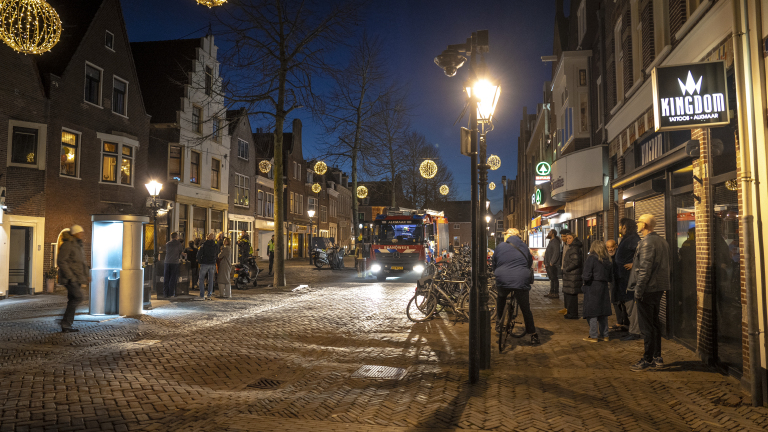 Straat in Alkmaar bij avond, versierd met verlichte bollen en een brandweerwagen op de achtergrond.