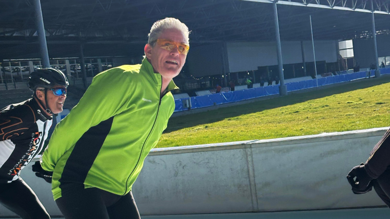 Twee mannen in sportkleding schaatsen buiten op een ijsbaan.