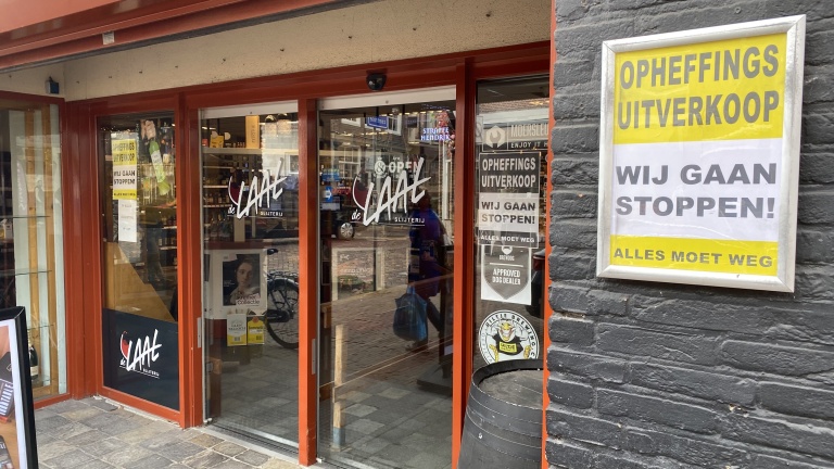 Winkel met opheffingsuitverkoop en posters met tekst "Wij gaan stoppen! Alles moet weg".