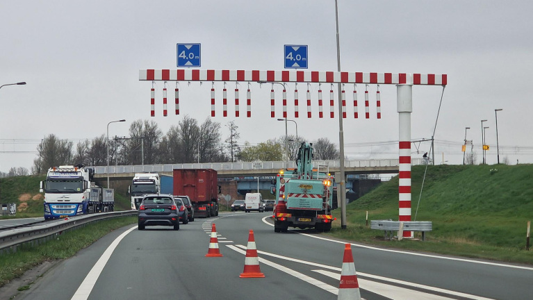 Wegwerkzaamheden met kegelafzettingen en een hoogtebeperking van 4 meter aangegeven door borden en staven boven de weg.