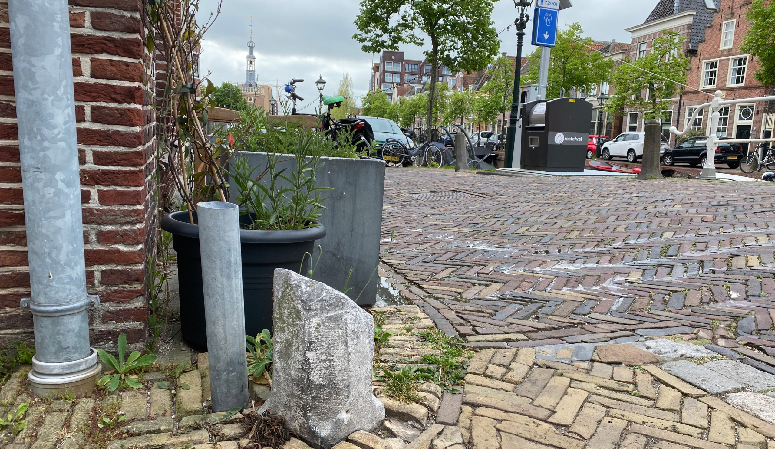 Straatbeeld in een stad met klinkers, fietsen en een zichtbare kerktoren in de achtergrond.