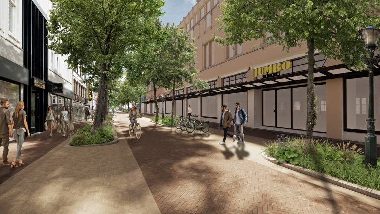 Straatbeeld met een wandelpad en verschillende winkels, waaronder een Jumbo-supermarkt. Mensen lopen en fietsen langs het voetpad en er staan fietsen geparkeerd. De straat is omgeven door bomen en groene beplanting. Het is een zonnige dag.