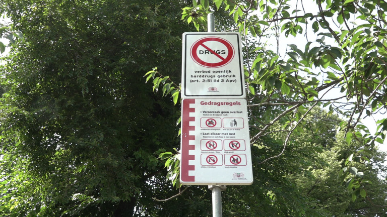 Bord met verboden en gedragsregels in een groene, boomrijke omgeving.