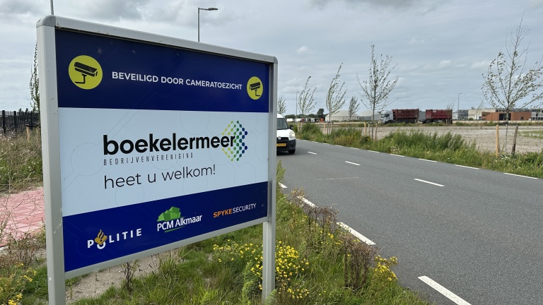 Bord langs de weg met tekst "boekelermeer bedrijventerrein heet u welkom" en iconen van onder andere een beveiligingscamera.