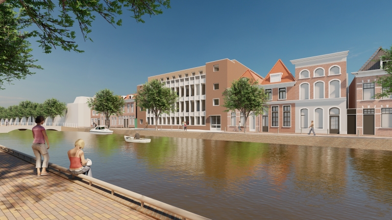 Straat langs een kanaal met enkele mensen op de kade, omgeven door bakstenen gebouwen en bomen, onder een blauwe hemel.