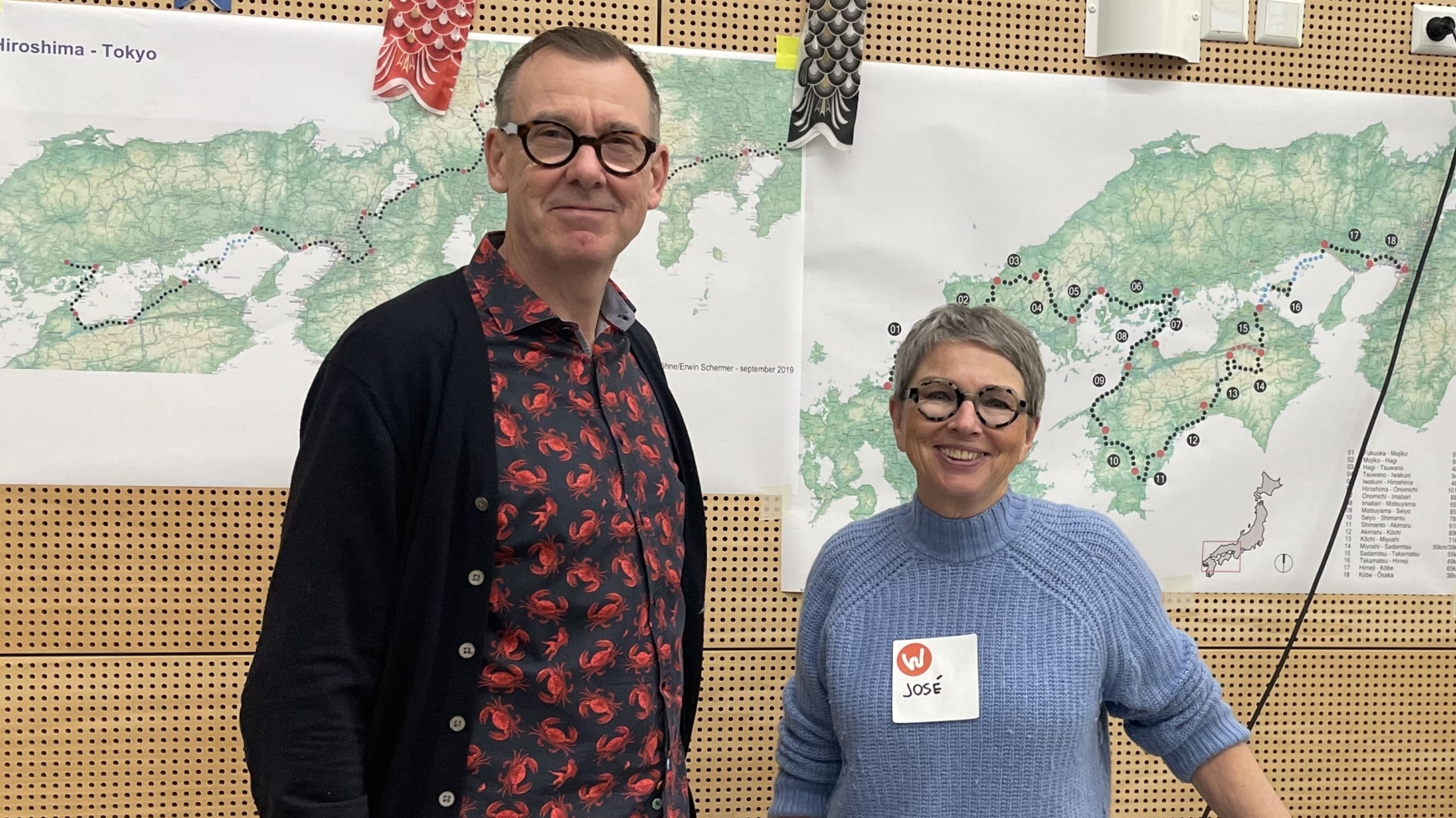 Twee mensen staan voor een kaart van Japan met inscripties "Hiroshima - Tokyo" en "Japan. Van Fukuoka naar Osaka."