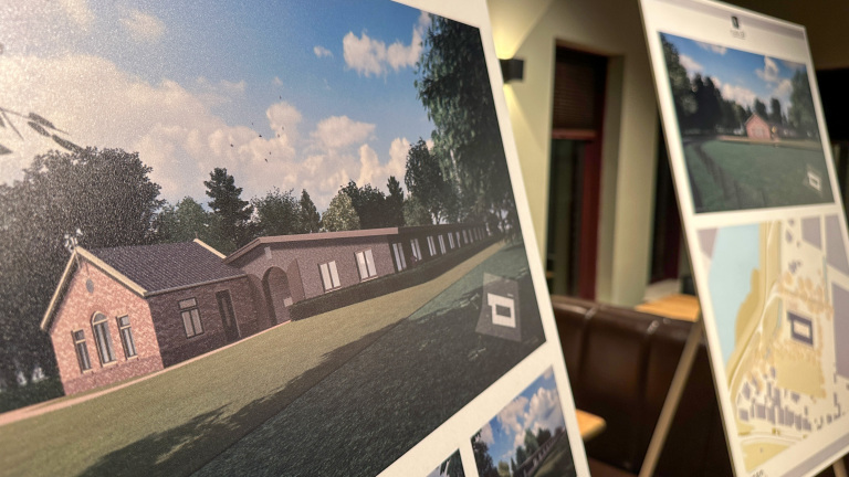 Borden met architecturale ontwerpen en plattegronden voor gebouwen, tentoongesteld in een binnenruimte.