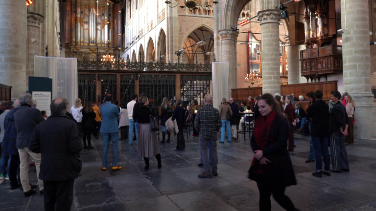 Mensen verzamelen zich in een grote kerk met een indrukwekkend orgel en middeleeuwse architectuur.