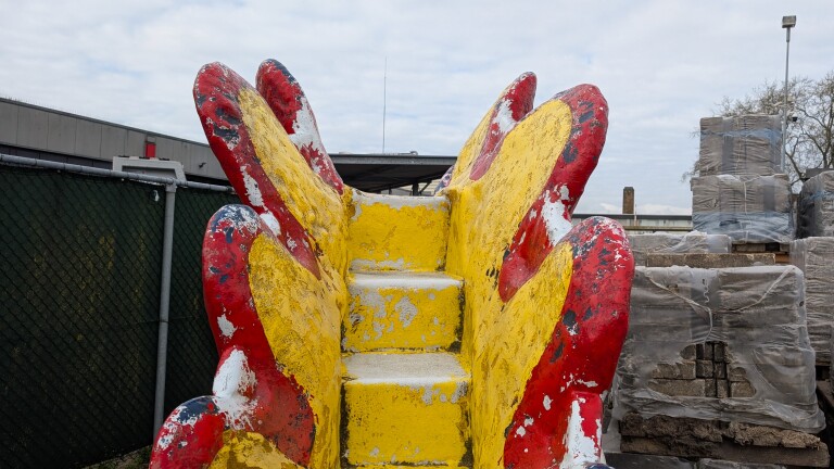 Beschilderde betonnen trap met felrode en gele tinten, omgeven door bouwelementen.