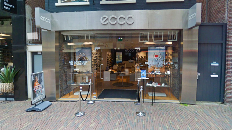 Winkelpui van een ECCO-winkel met glazen deuren, posters met de teksten "GO ANYWHERE IN COMFORT" en "INSPIRED BY NATURE".