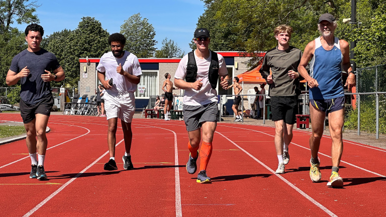 Vijf mannen joggen naast elkaar op een atletiekbaan op een zonnige dag.