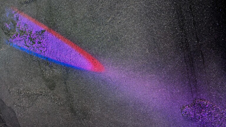 Rode en paarse lichtprojectie op een donkere, korrelige ondergrond.