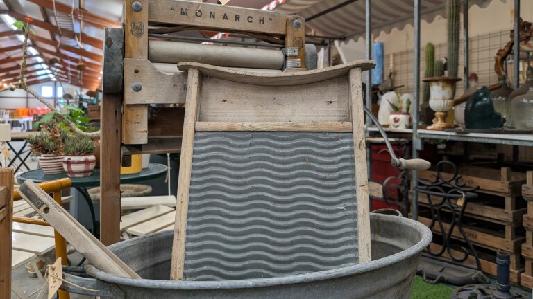 Ouderwets wasbord met geribbelde metalen plaat in een zinken teil, met houten wringer erboven op een rommelige markt
