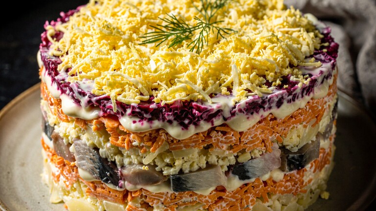 Gelaagde salade zoals haring onder een bontjas met lagen groenten, mayonaise en geraspte eieren, gegarneerd met dille