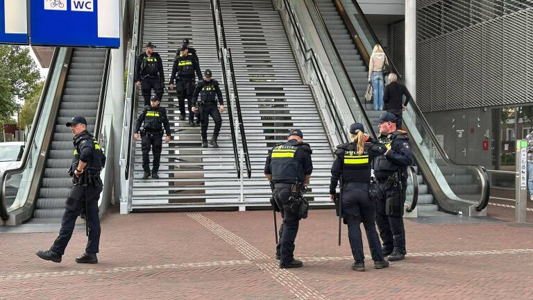 Groep politieagenten bij trappen en roltrappen van een station, terwijl enkele agenten de trap afdalen