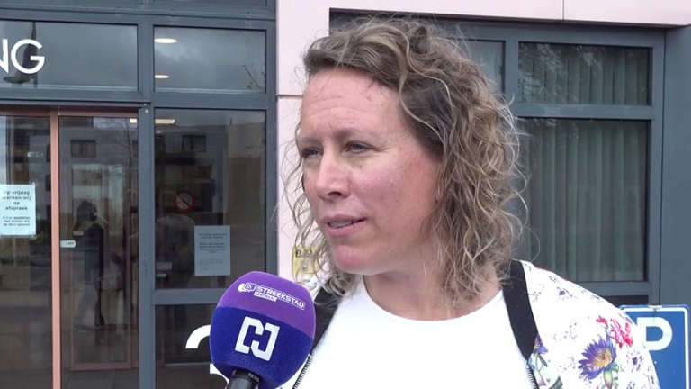 Vrouw met krullend haar wordt buiten een gebouw geïnterviewd met een paarse microfoon van Streekstad Centraal