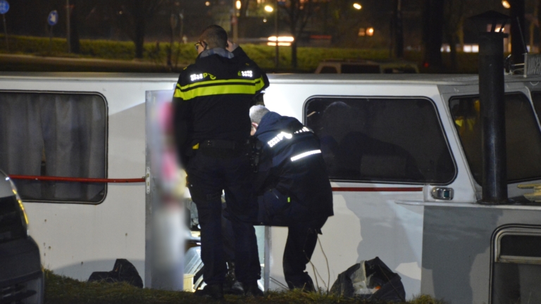 Meerdere politieauto's staan geparkeerd langs een weg in de nacht, met agenten bij een voertuig.