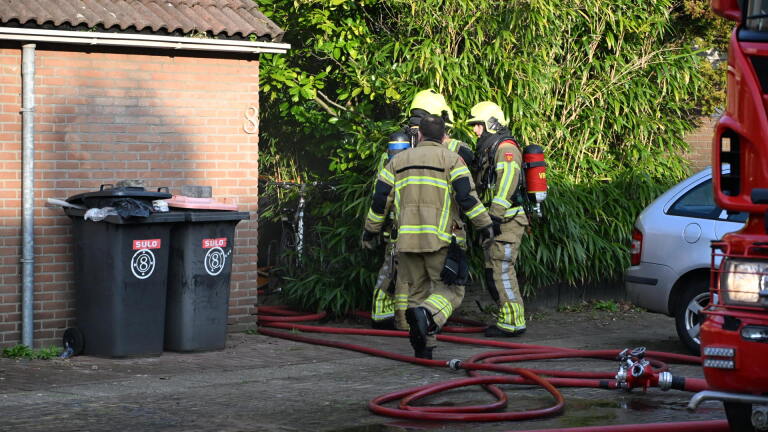 Rook stijgt op uit een schoorsteen van een huis met zonnepanelen op het dak.