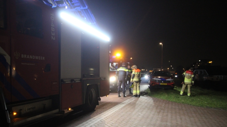 Brandweerlieden op een reddingsboot uitvoeren een nachtelijke operatie op een meer, verlicht door felle lichten.