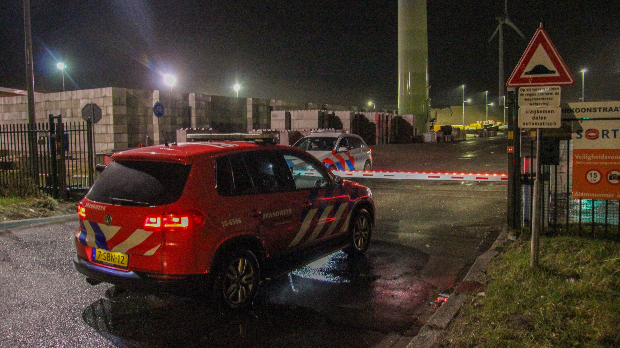Industriepand van Sortiva bij nacht, met rode containers ervoor en verlichting die het terrein verlicht.