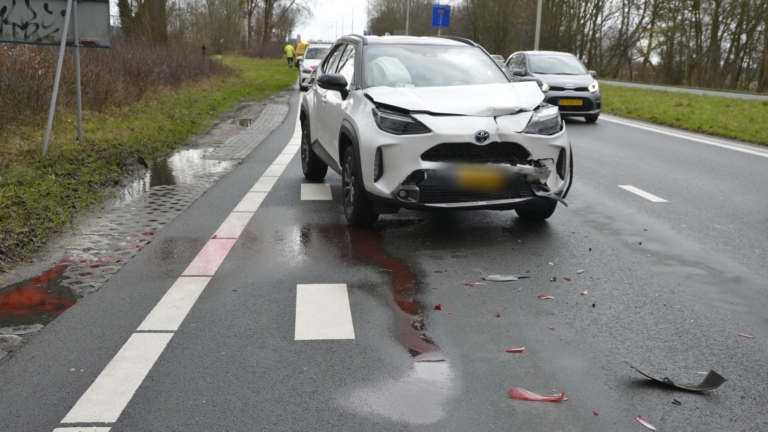Auto-ongeluk met meerdere voertuigen langs een weg; ambulancepersoneel is aanwezig, en er staat een ambulance geparkeerd.