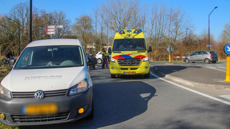 Scootmobiel op een kruispunt met politieagenten en een politiewagen op de achtergrond.