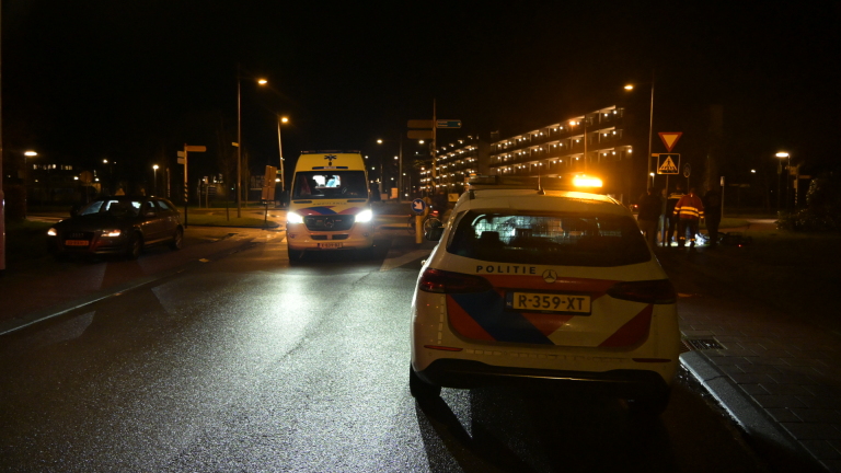 Politieagenten controleren 's nachts een fiets op een troittoir; een man kijkt toe.
