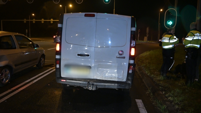 Verkeersongeluk in de nacht bij een kruispunt; ambulance en verschillende auto's aanwezig met politie en verkeerslichten op groen.