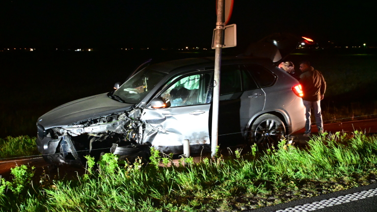 Auto met zware schade aan de voorkant staat op een sleepwagen in het donker.