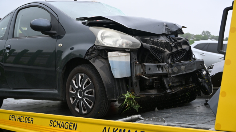 Beschadigde auto met ingedeukte voorkant op een gele sleepwagen.