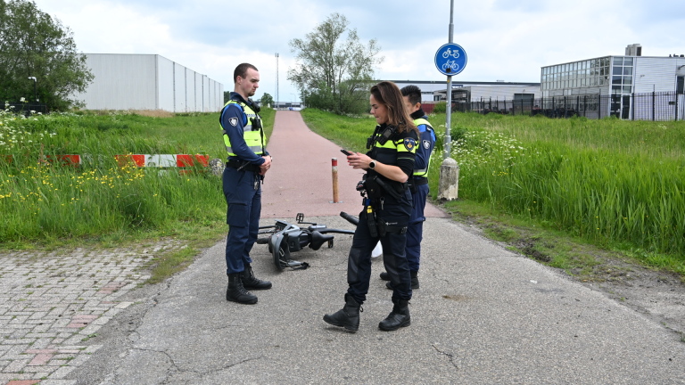 Politieagenten bespreken een incident met een omgevallen scooter op een fietspad.