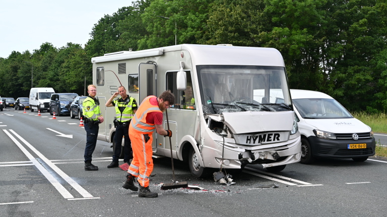 Verfrommeld voertuig betrokken bij ongeval langs de weg, met een brandweerman en een hulpverlener naast een ambulance.