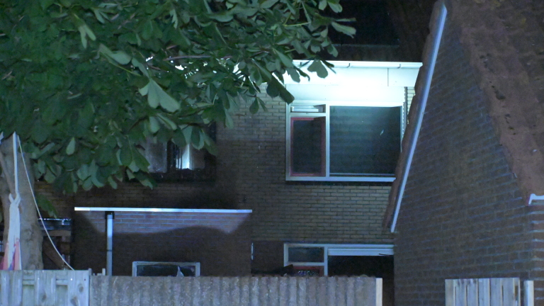 Brandweerwagens staan 's nachts geparkeerd voor een flatgebouw, met brandweerlieden aanwezig en heldere lichten aan.