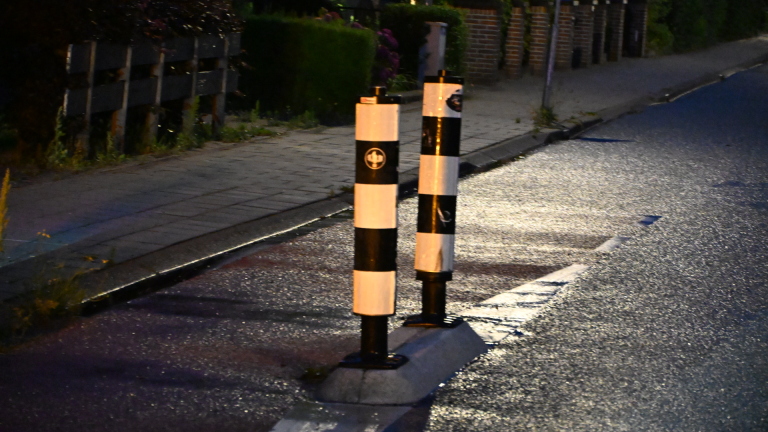 Een politieauto en een ambulance staan 's nachts op een donkere weg geparkeerd.