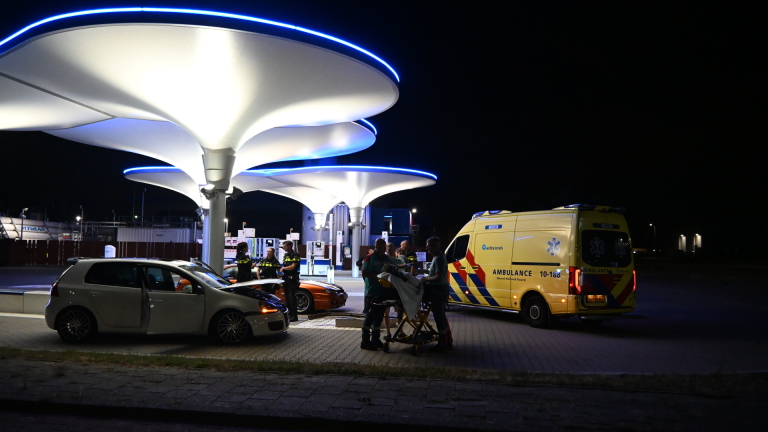 Ambulance en politie bij twee auto’s na een incident bij NXT, met een witte auto met open portier en een rode coupé