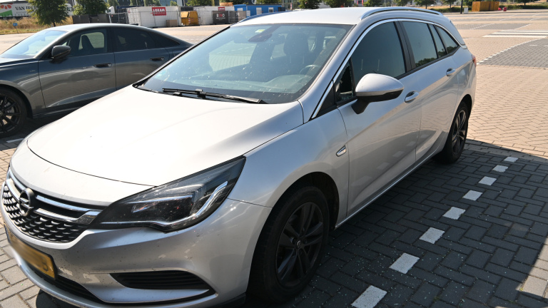 Kapotte zijruit van een auto met gebroken glas in het portier en zichtbare veiligheidsgordel binnenin