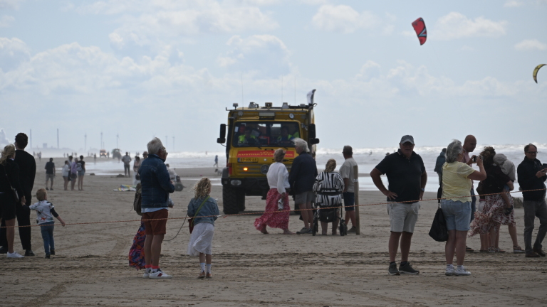Reddingsbrigade in oranje rubberboot vaart over ruwe zee, met windturbines op de horizon