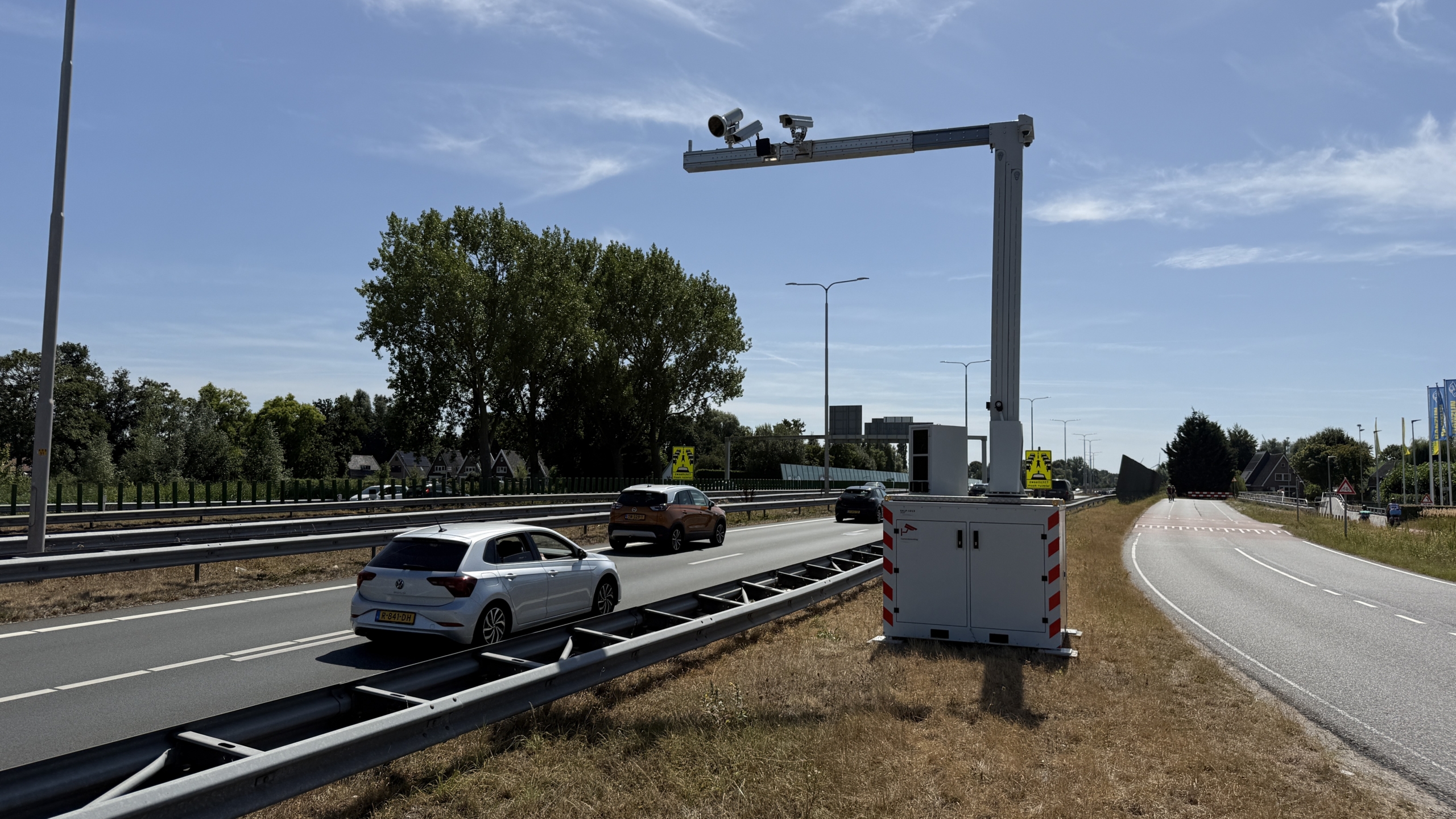 Wegwerkzaamheden langs de snelweg met afgezette rijstrook, werkvoertuig met hoog platform en verkeer ernaast