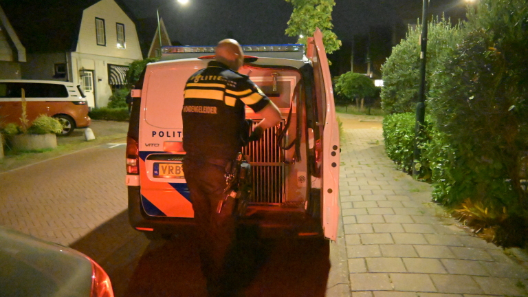 Ambulance met zwaailichten staat ’s avonds in woonstraat; brommer op voorgrond en fiets ligt op de grond links
